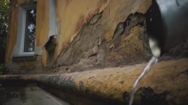 Rusya'da harap eski ev. Şiddetli yağmur, çatıdan gelen su demir bir borudan alçalıyor. Duvarlar yıkılıyor, evler çürüyor. Şehrin yoksul sakinleri yardım.