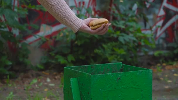 ハンバーガーはゴミ箱に投げ込まれる 健康的な食べる人々 若い女の子の手は 緑の容器にジャンクフードにさよならを言う — ストック動画