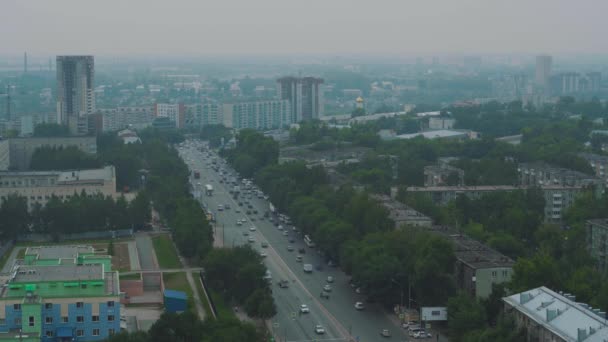 街は霧の中で 車は道路に沿って運転しています 高速道路の屋根からの眺め 緑の木が歩道に沿って育つ ロシアの滑らかな道 — ストック動画