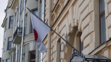 Japon bayrağı eski sarı mimari bir binanın arka planında gelişiyor. Rusya 'daki Japonya Konsolosluğu.
