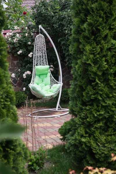 White chair - teeter-totter. The metal chair in a garden for rest