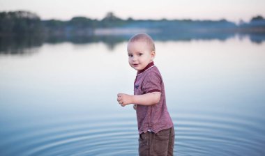 bahar gününde güzel bir nehirde sıçramasına komik sarışın küçük çocuk. Çocuk giyim su gölden sualtındaki
