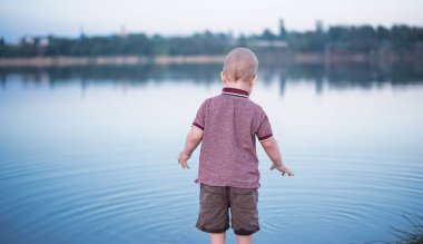 Açık havada akşam güzel bir çocuk. Çocuk göl kenarında yürüyor
