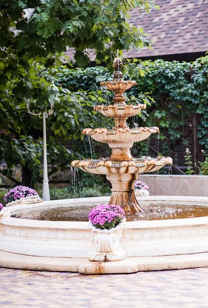 Fountain in garden. The working fountain in the summer in a garden. Water flows and splashes in the fountain