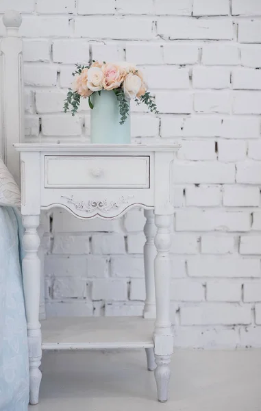 Beautiful flowers in a box of soft blue color and stand on a carved wooden pedestal. the interior in the room girls