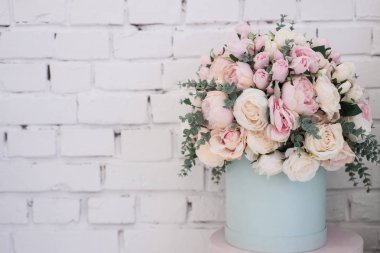 Beyaz tuğla duvar arka plan üzerinde yuvarlak bir kutu içinde toplu yapay çiçekler