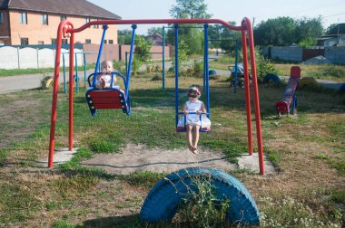 Çocuklar parkta salıncakta sallanır. Açık havada çocukluk.