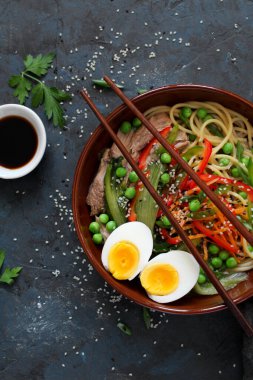 Sığır etli, sebzeli ve yumurtalı erişte. Arka planda koyu renk. Fotokopi alanı olan üst manzara. Asya yemekleri.