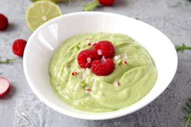 Hafif arka planda ahududu ile servis edilen ev yapımı avokado smoothie. Diyet yemek. Kopyalama alanı olan üst görünüm.