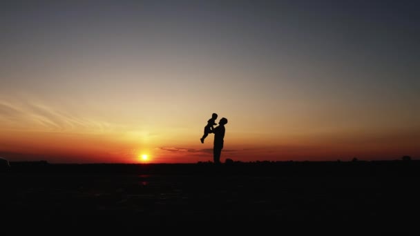 Bir baba ile küçük oğlu günbatımında oynarken siluetleri — Stok video