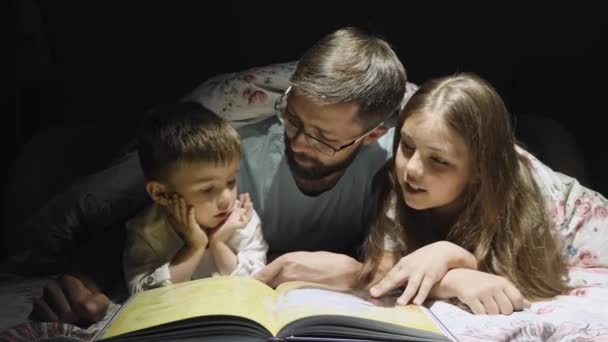 Отец читает сказку для детей на ночь — стоковое видео