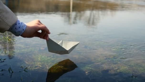 Дитина біля ставка з паперовим човном — стокове відео