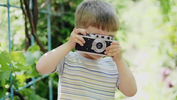 Портрет маленького мальчика, фотографирующего на винтажную камеру — стоковое видео