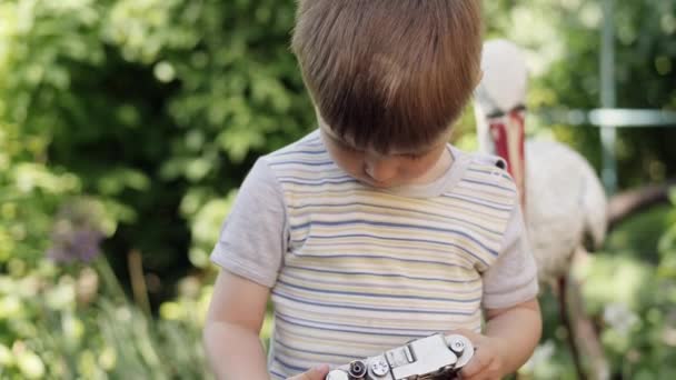 Retrato de un chico lindo tomando fotos al aire libre en la cámara vintage — Vídeo de stock