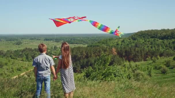 Niño y niña sosteniendo una cometa voladora — Vídeos de Stock