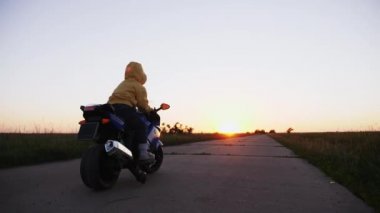 Üç yaşında bir yolda bir oyuncak motosiklet Binme bir çocuk