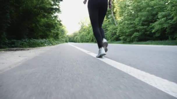 Бегунья бежит по открытой дороге в сельской местности — стоковое видео