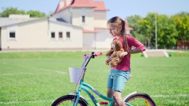 Retrato de una linda niña sentada en una bicicleta — Vídeo de stock