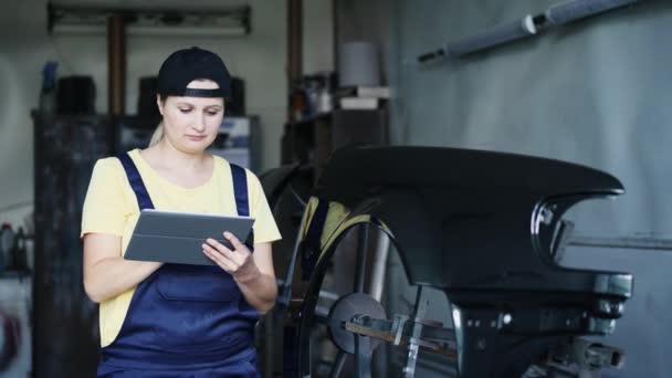 Kvinnan arbetar med en digital tablett i garaget för bilreparationer — Stockvideo