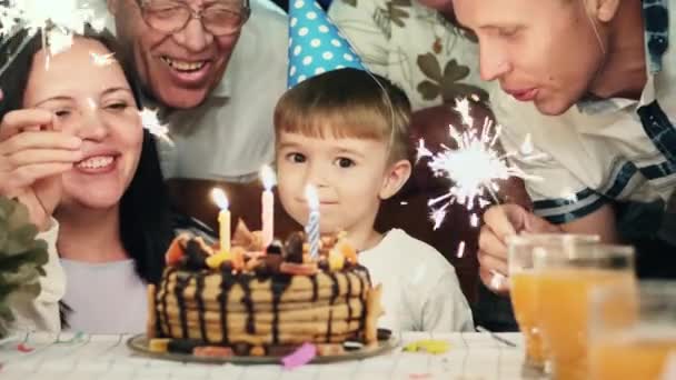 Niño en sombrero de cono soplando velas en pastel de cumpleaños — Vídeos de Stock