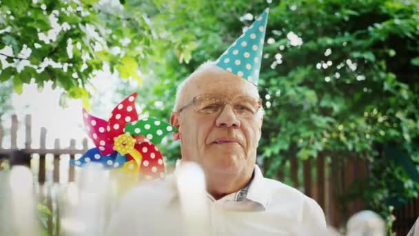 Portret van een gelukkig oudere man met een feestelijke cap op zijn hoofd — Stockvideo