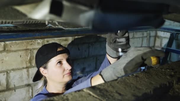 Bonito mecânico feminino repara um carro em um hangar — Vídeo de Stock