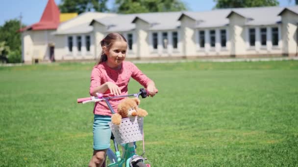 Portret van een schattig klein meisje zittend op een fiets met speelgoed — Stockvideo