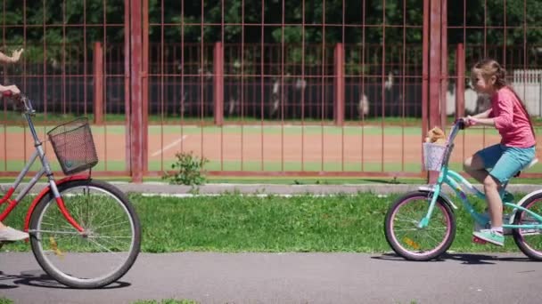 Dos chicas montan bicicletas al aire libre — Vídeo de stock