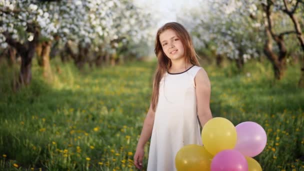 Portret van een jong meisje in een bloeiende appelboomgaard — Stockvideo