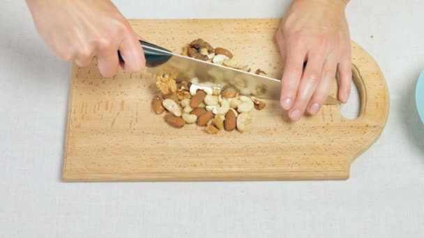 Chefs hembras manos picando nueces mixtas en tabla de cortar de madera — Vídeos de Stock