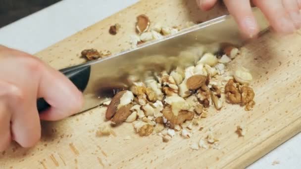 Chefs manos picando nueces mixtas en tabla de cortar de madera — Vídeos de Stock