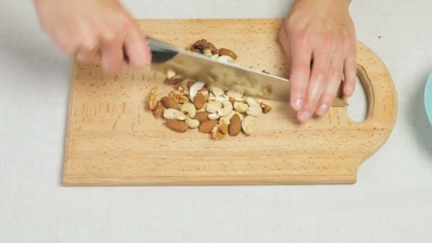 Kvinnliga kockar händerna hugga blandade nötter på trä skärbräda — Stockvideo