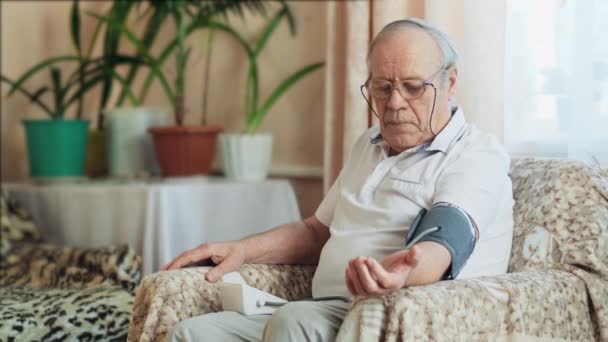 Un anciano mide la presión arterial en casa — Vídeos de Stock