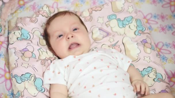 El bebé estornuda acostado boca arriba en la cama. — Vídeos de Stock