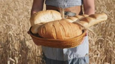Bir kadın bir buğday alandan sepetin içinde ekmek taşıyor