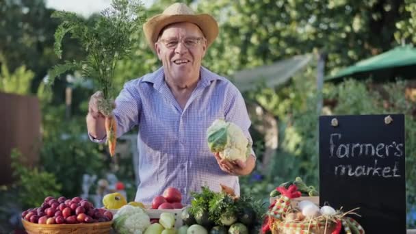 Un agricultor de edad avanzada está vendiendo verduras en el mercado agrícola — Vídeo de stock