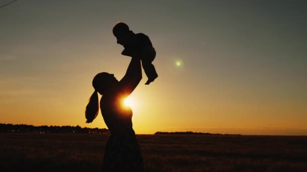 Силуэт матери с ребенком на закате — стоковое видео