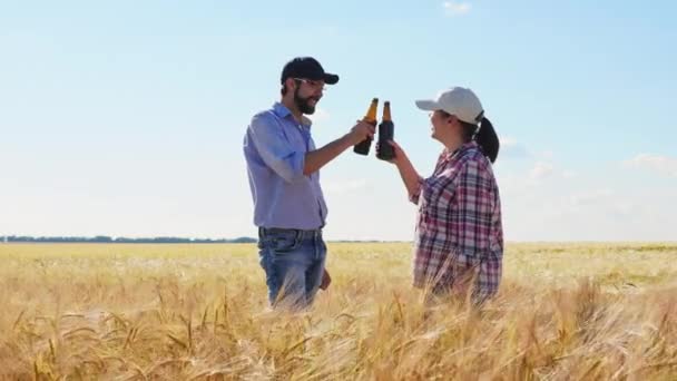 Два фермера пьют пиво из бутылок — стоковое видео
