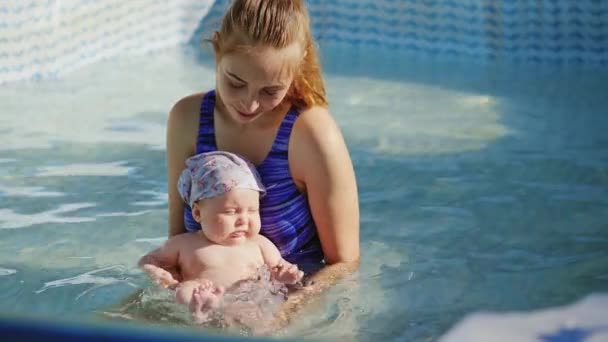 Mother holding her daughter and she having fun in swimming pool — Stock Video
