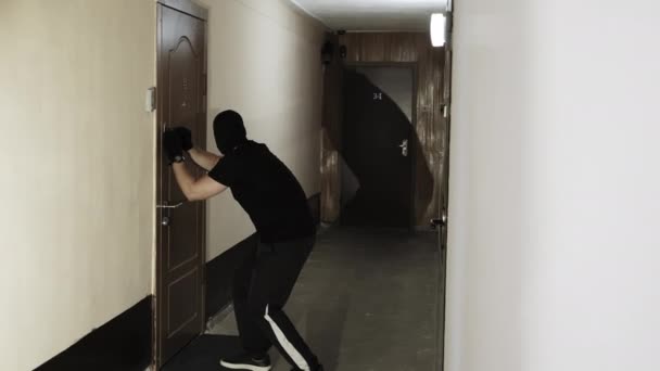 Een mannelijke dief probeert te openen van de deur met behulp van een hoofdsleutel — Stockvideo