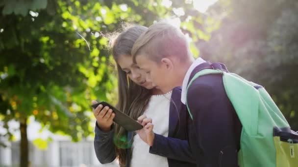 Хлопчик і дівчинка використовують цифрову книгу на відкритому повітрі — стокове відео