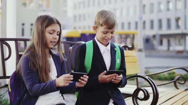 Seorang anak laki-laki dan perempuan menggunakan smartphone dan tablet — Stok Video