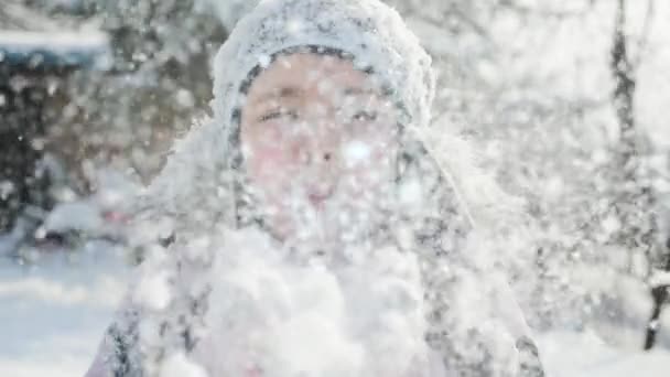 Красивая девушка, дующая в снег — стоковое видео
