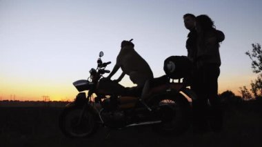 Yan görünümü siluet: bir çift aşık bisikletçileri ile birlikte mesafe bakarak bir motosiklet üzerinde oturan bir köpek
