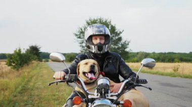 Açık havada bir motosiklet üzerinde oturan bir köpek ile motorcu