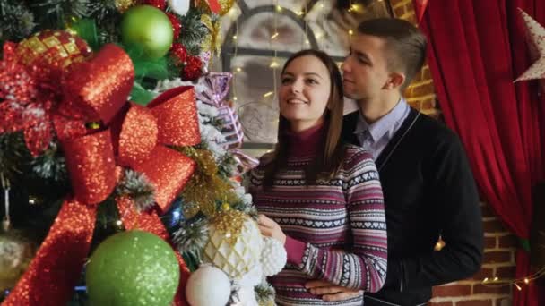 Pareja joven decorando un árbol de Navidad en casa — Vídeos de Stock