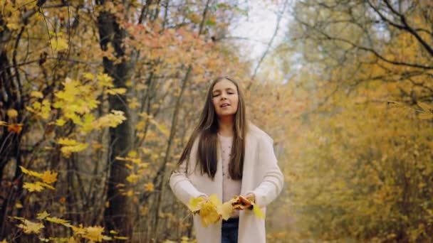 Улыбающаяся девочка-подросток и блюющая в осеннем лесу — стоковое видео