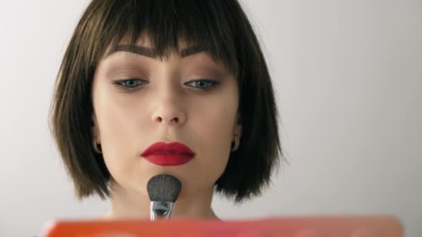 Красивая девушка макияж себя перед зеркалом — стоковое видео