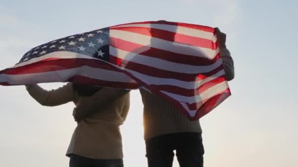 Vue arrière famille patriotique avec un grand drapeau de l'Amérique — Video