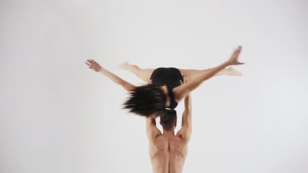 Мужчина-спортсмен поворачивает девушку, держащую бюст на вершине — стоковое видео